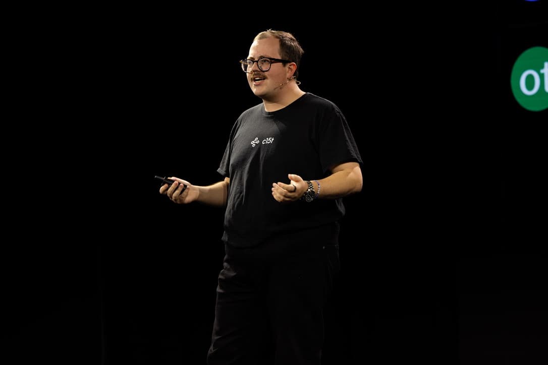 Christopher Burns speaking on stage in a c15t T-shirt